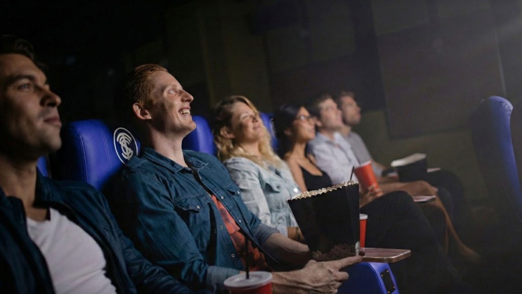 Persona sentadas en sillas de cine viendo una película