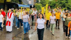 Personas en procesión con ramos de palama de cera